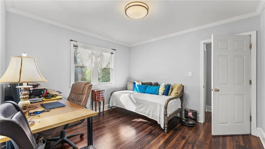 Bedroom featuring a desk, ornamental molding, and dark wood-type flooring
