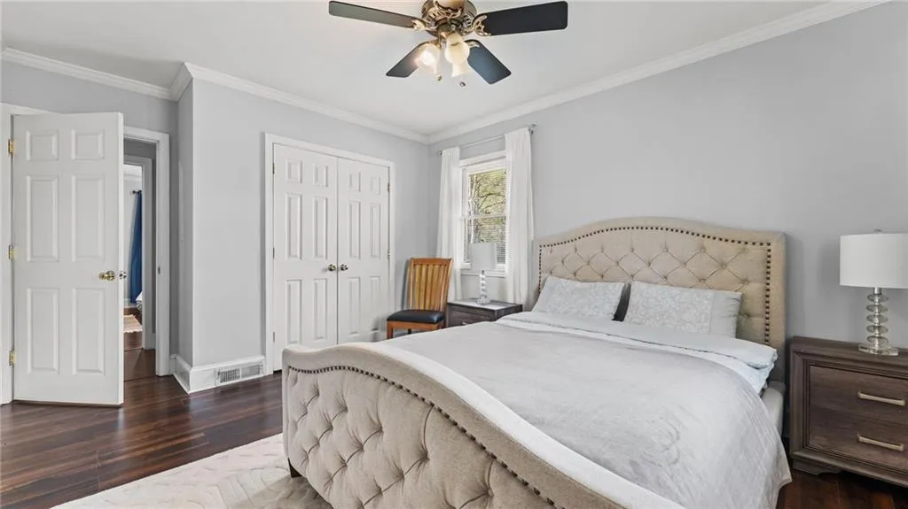 Bedroom featuring dark wood-style floors, ornamental molding, a closet, and a ceiling fan