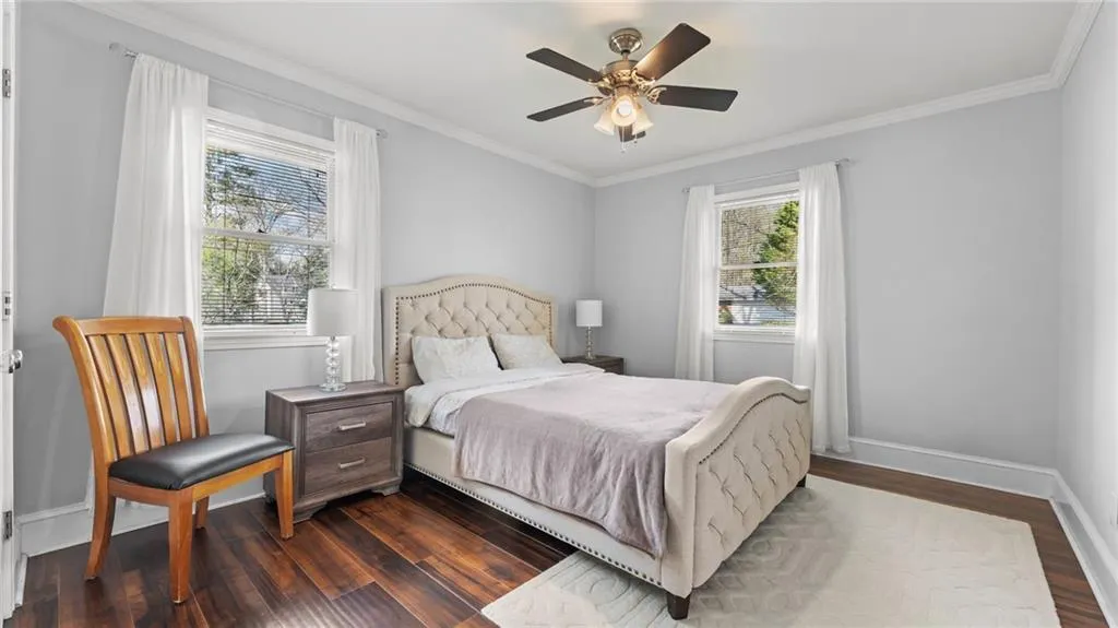 Bedroom with dark wood-type flooring, ornamental molding, and a ceiling fan