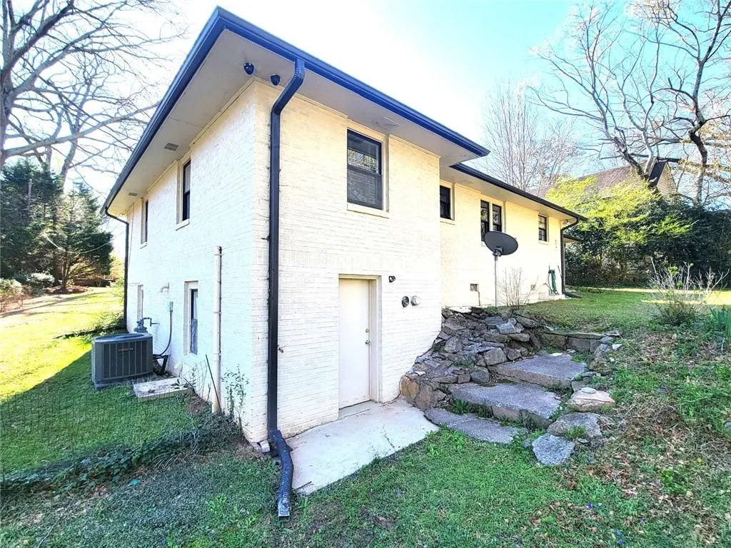 View of side of property featuring a lawn and brick siding