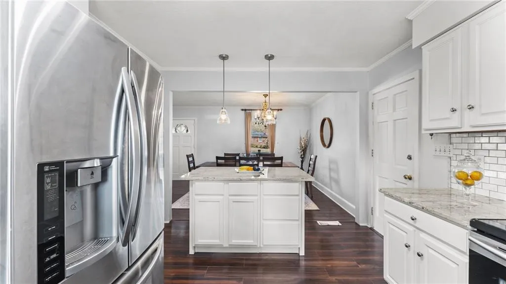 Kitchen featuring stainless steel fridge with ice dispenser, white cabinets, dark wood-type flooring, and crown molding