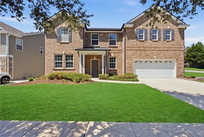 Brick facade with white trim, covered front entry, attached two-car garage, and a concrete driveway