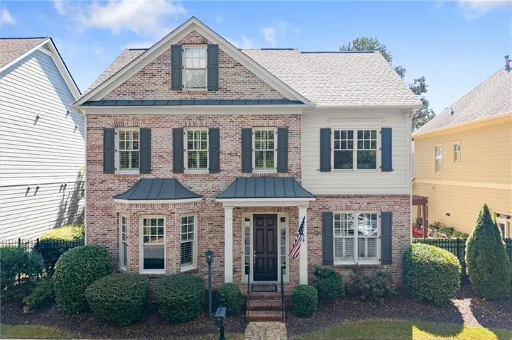 Brick and siding exterior with dark shutters, covered front porch, and bay window