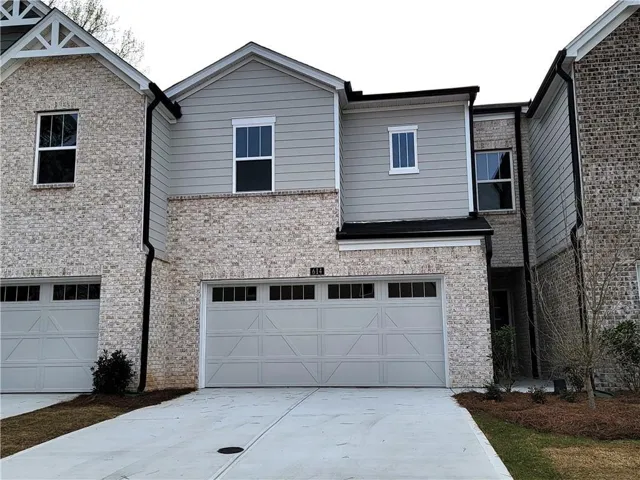 Contemporary townhome exterior featuring light-colored brick and horizontal siding