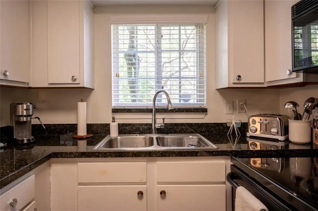 Kitchen featuring black microwave, electric range oven, and white cabinetry