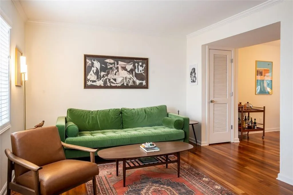 Living room with wood finished floors, crown molding, and plenty of natural light