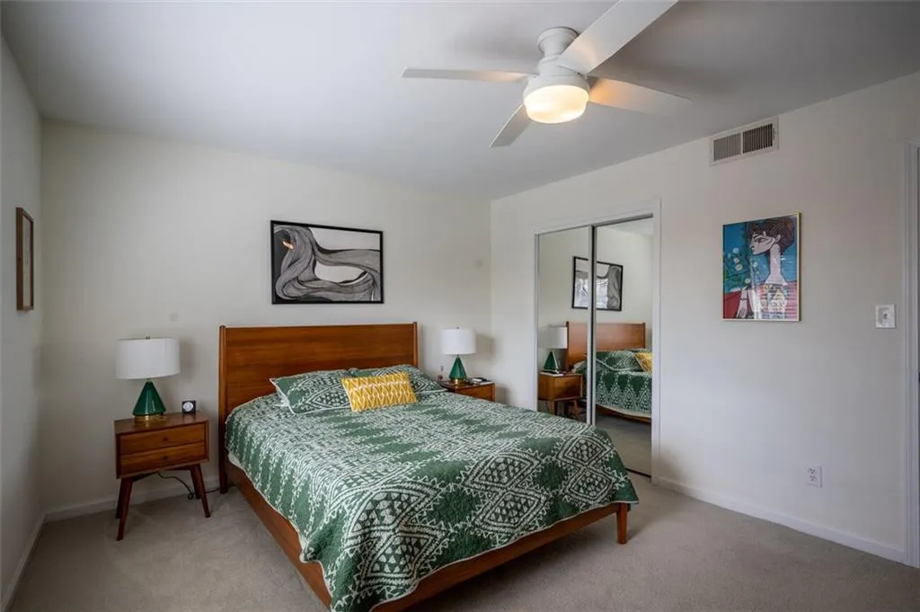 Bedroom with light colored carpet, a closet, and a ceiling fan