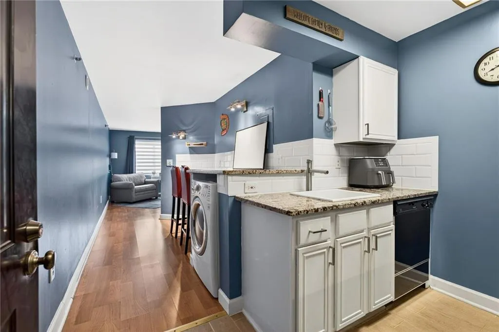 Kitchen with granite counters and bar with washer/dryer.