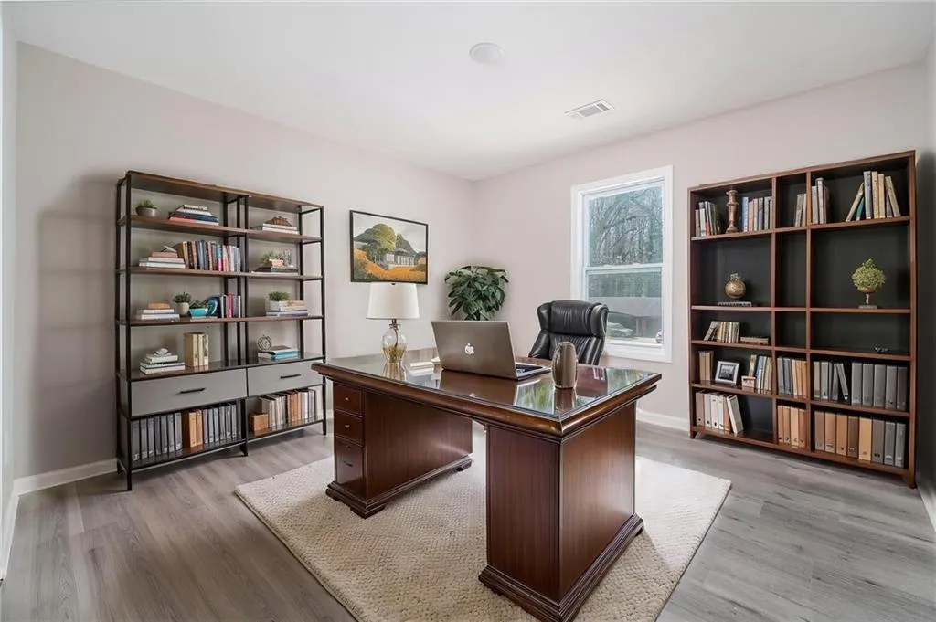 Office area with baseboards, visible vents, and light wood finished floors