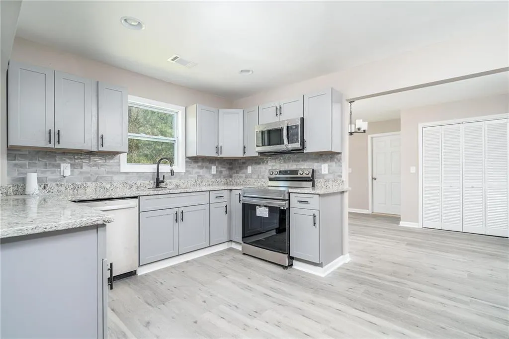 Kitchen featuring decorative backsplash, visible vents, light wood-style flooring, appliances with stainless steel finishes, and a sink