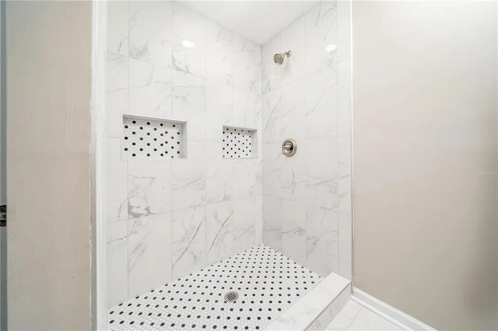 Full bath featuring baseboards and a tile shower