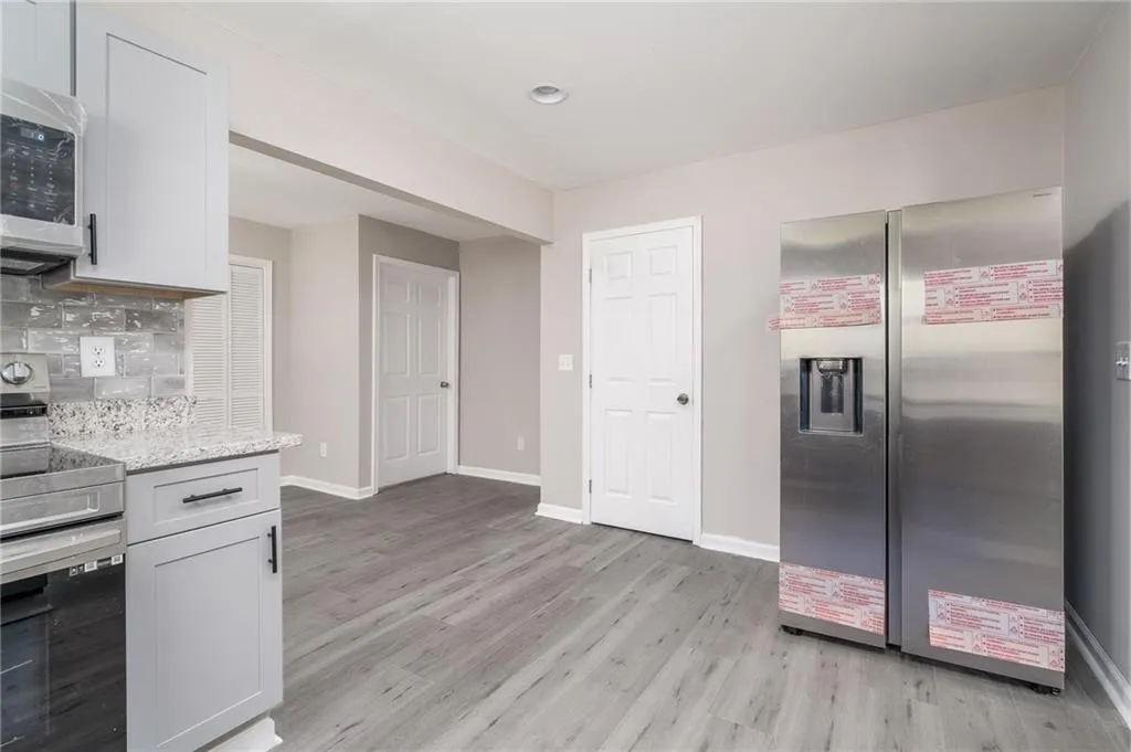 Kitchen featuring baseboards, tasteful backsplash, light wood-style floors, and appliances with stainless steel finishes