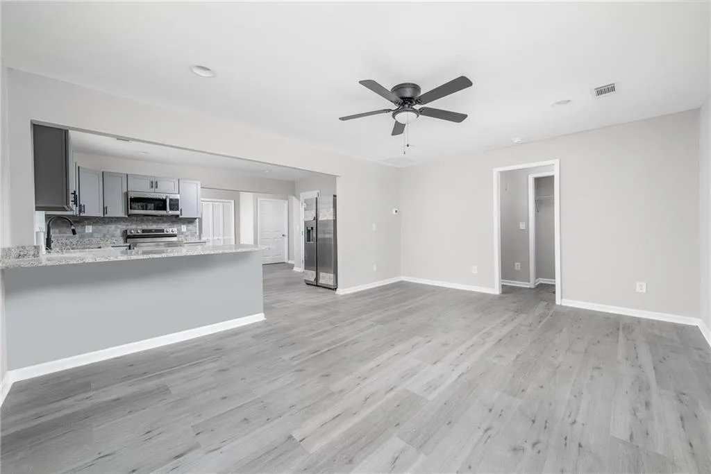 Unfurnished living room with baseboards, light wood-style flooring, ceiling fan, and visible vents