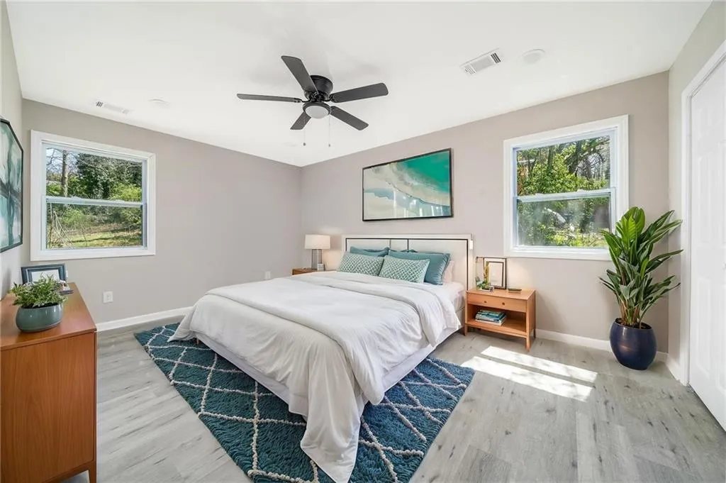 Bedroom with baseboards, ceiling fan, visible vents, and wood finished floors