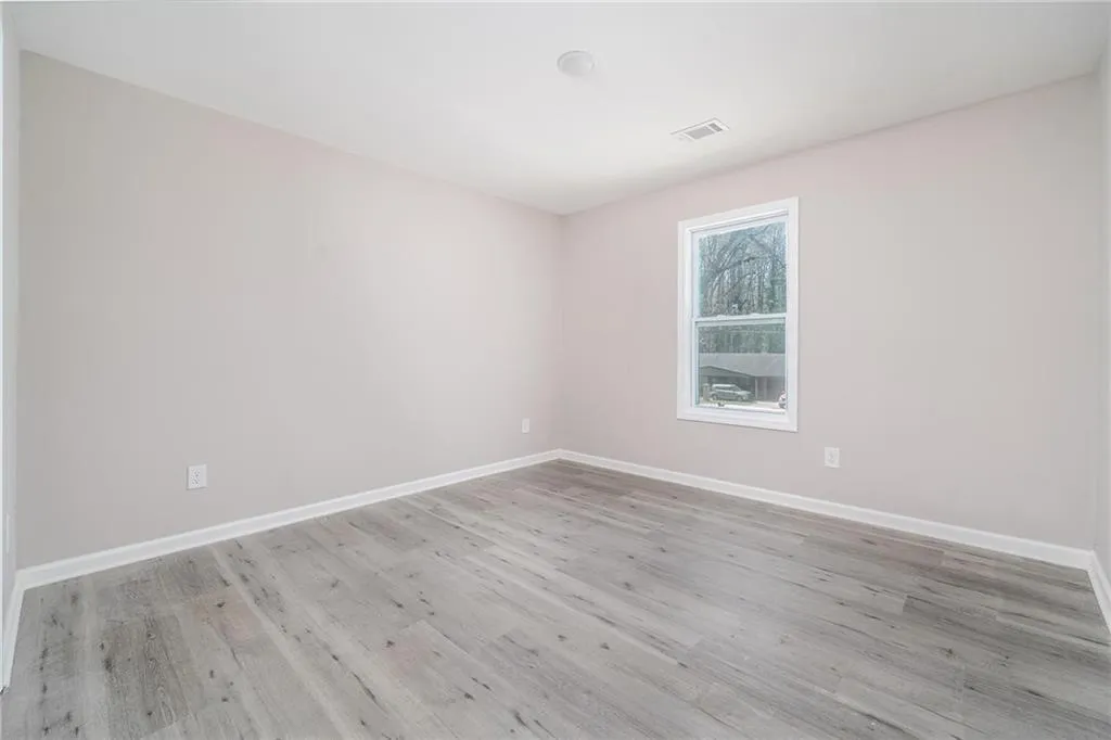Unfurnished room with baseboards, visible vents, and wood finished floors