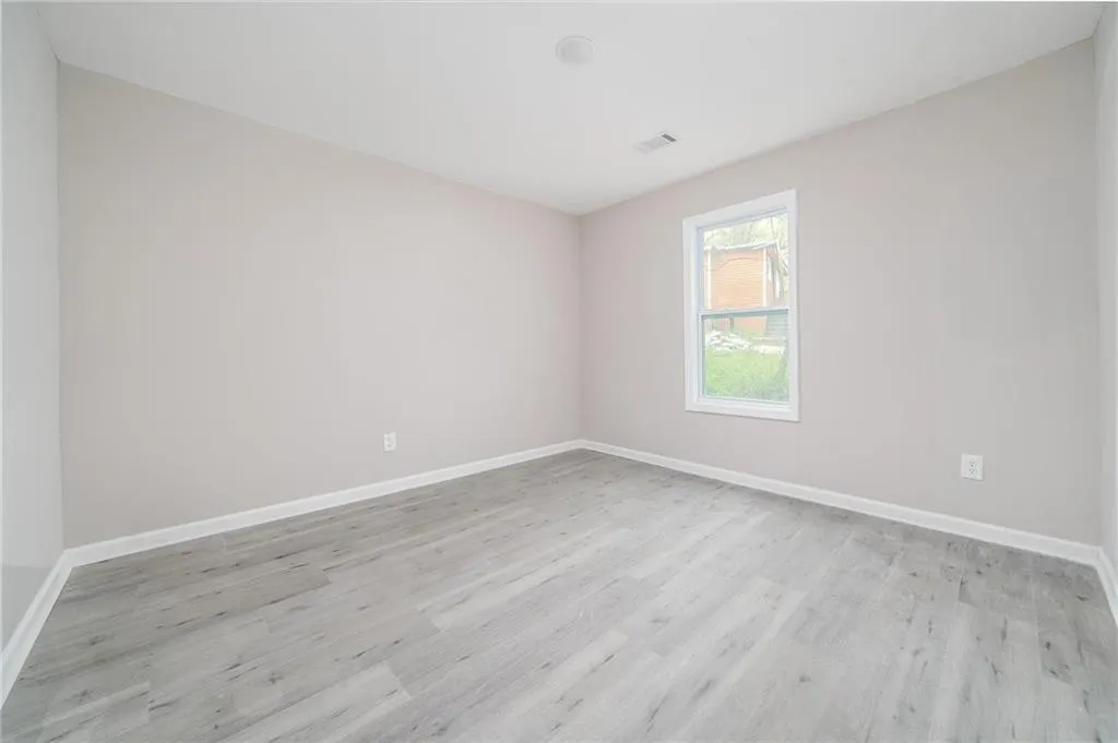 Empty room featuring baseboards, visible vents, and light wood-type flooring