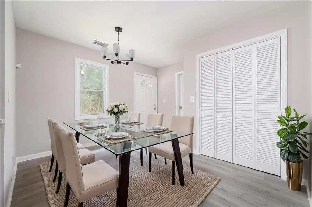 Dining space with baseboards, visible vents, wood finished floors, and a notable chandelier