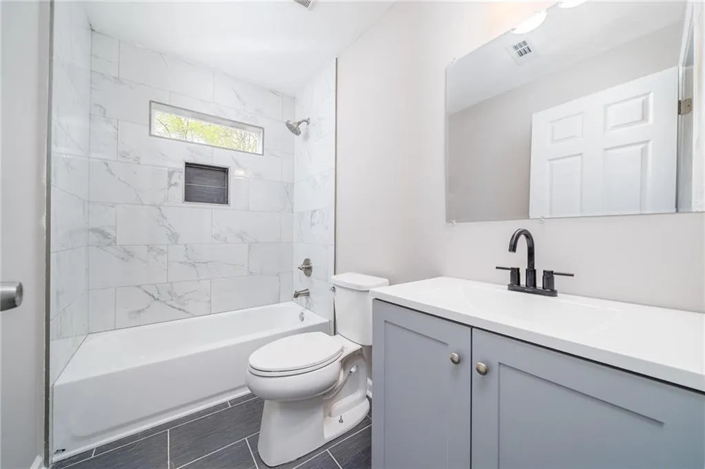 Bathroom with bathtub / shower combination, visible vents, toilet, and vanity