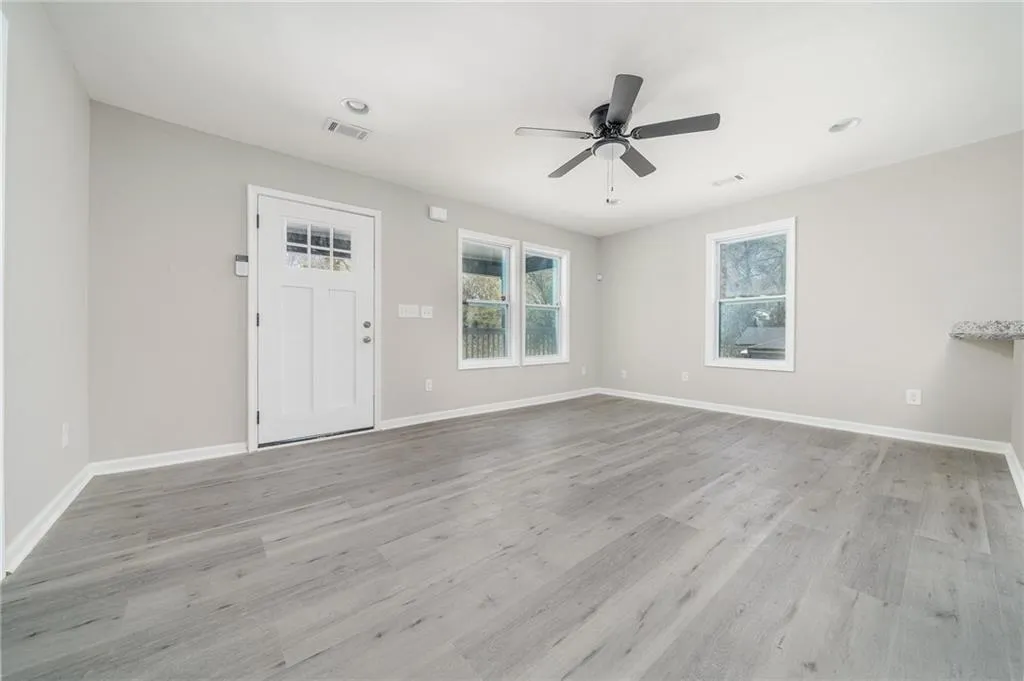 Unfurnished living room with light wood-type flooring, a ceiling fan, baseboards, and visible vents