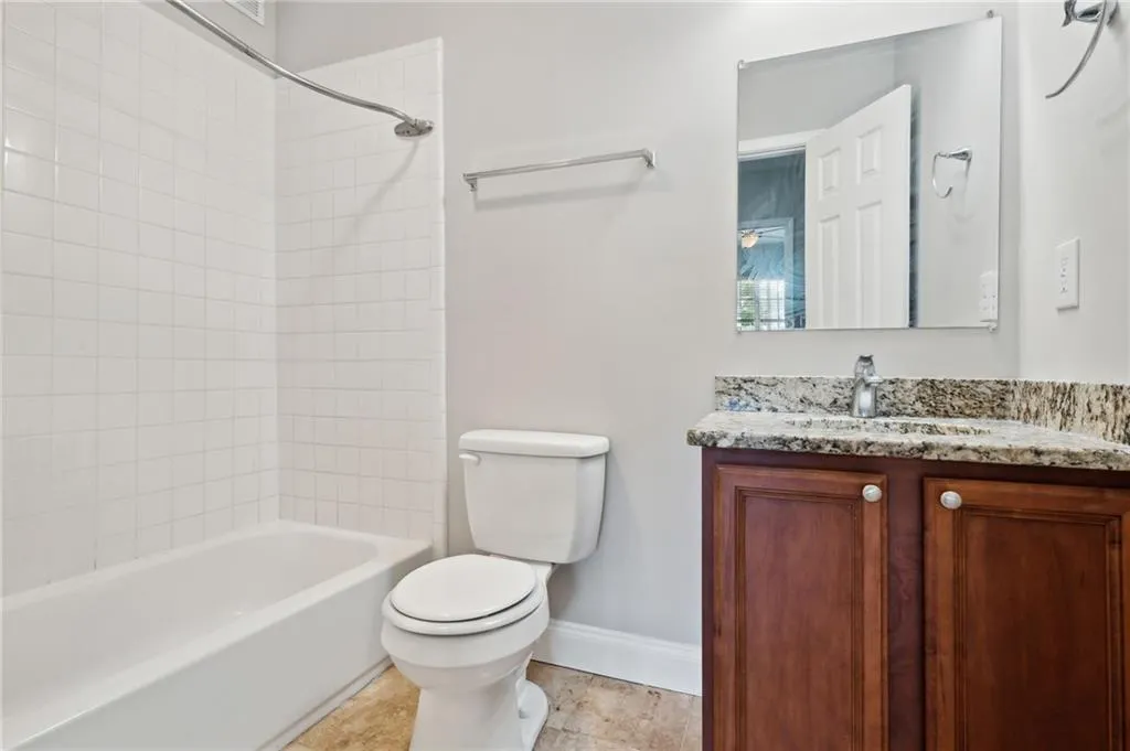 Full bathroom with tile patterned flooring, toilet, vanity, and tiled shower / bath combo