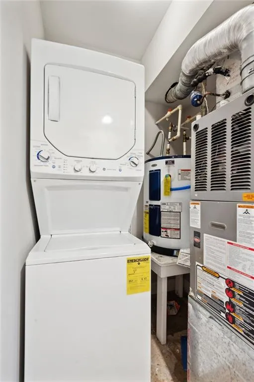 Laundry room with stacked washer and dryer and water heater