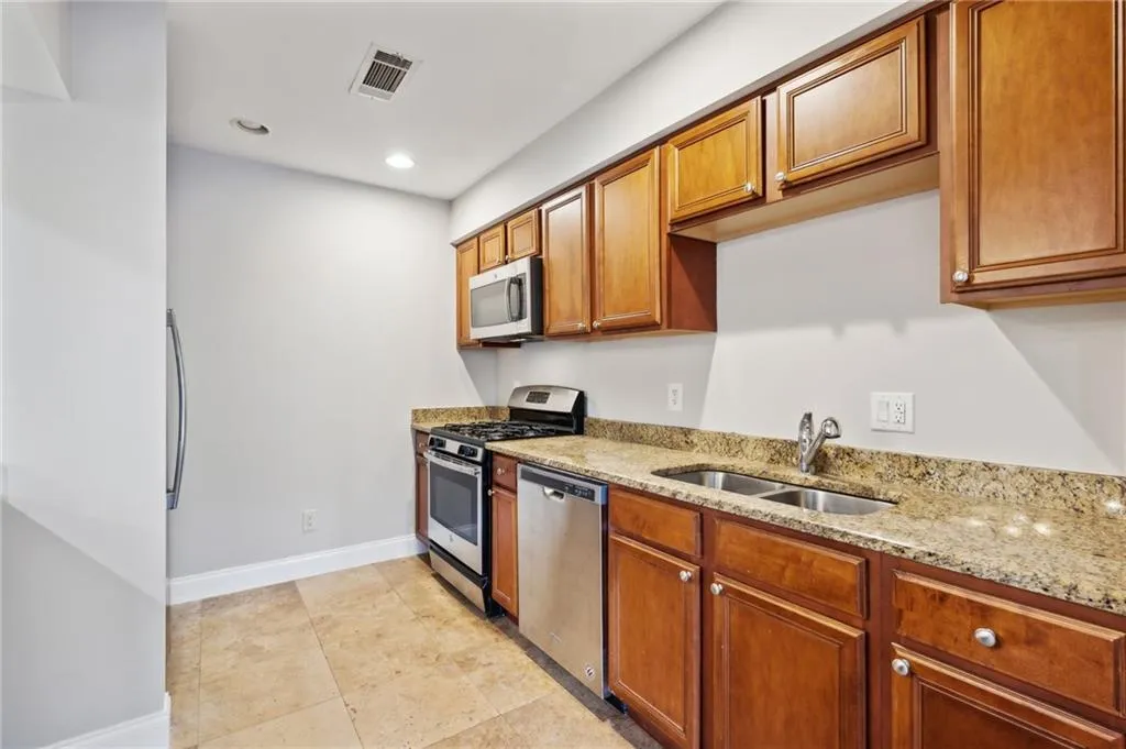 Kitchen featuring light tile flooring, stainless steel appliances, built in microwave, countertops, and double sink