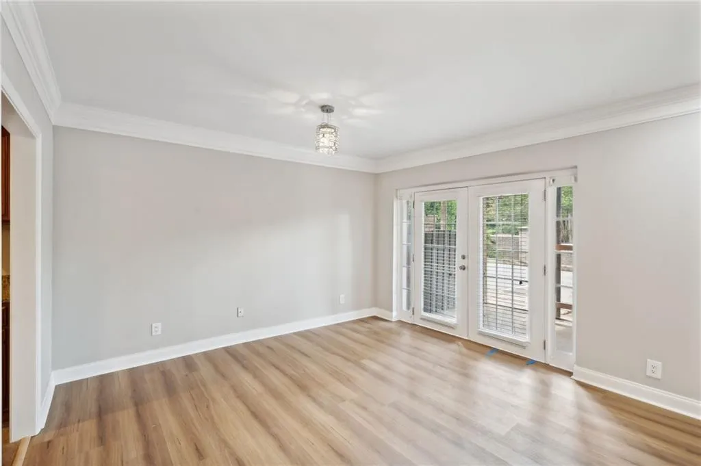 Room features french doors, crown molding, and light LVP