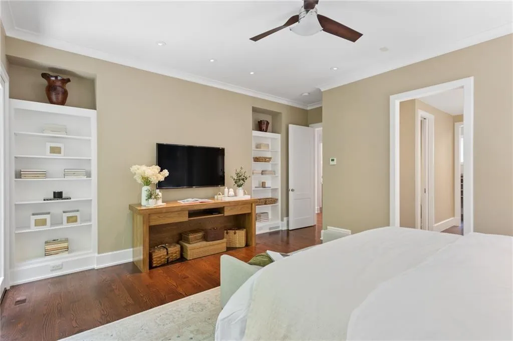 Dark wood-finish flooring, built-in shelving, recessed lighting, crown molding, and a ceiling fan with integrated lighting