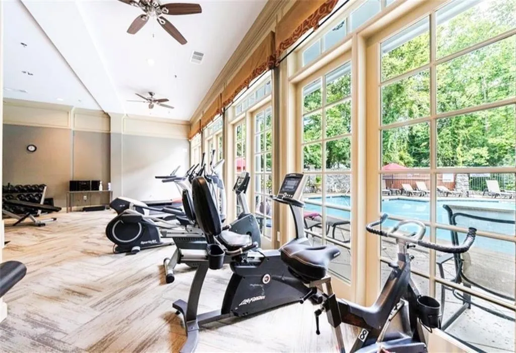 Exercise room featuring carpet, visible vents, a ceiling fan, and ornamental molding