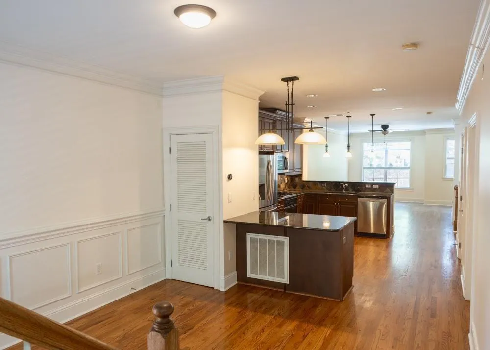 Kitchen with a peninsula, stainless steel appliances, a sink, dark countertops, and ornamental molding