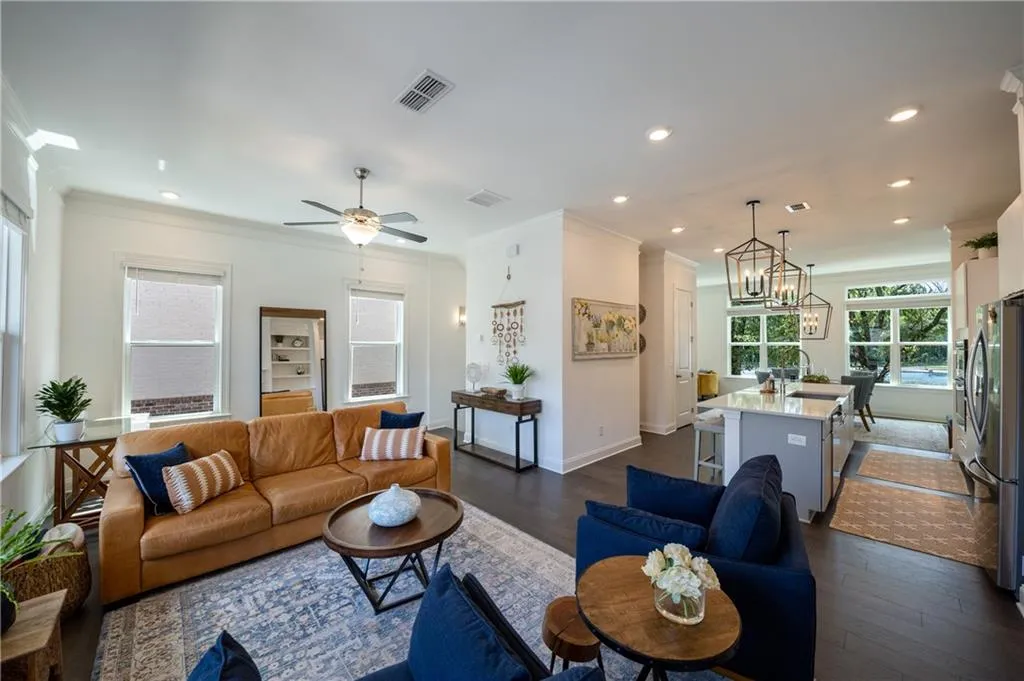 Living room featuring dark wood finished floors, ornamental molding, recessed lighting, a ceiling fan, and a chandelier