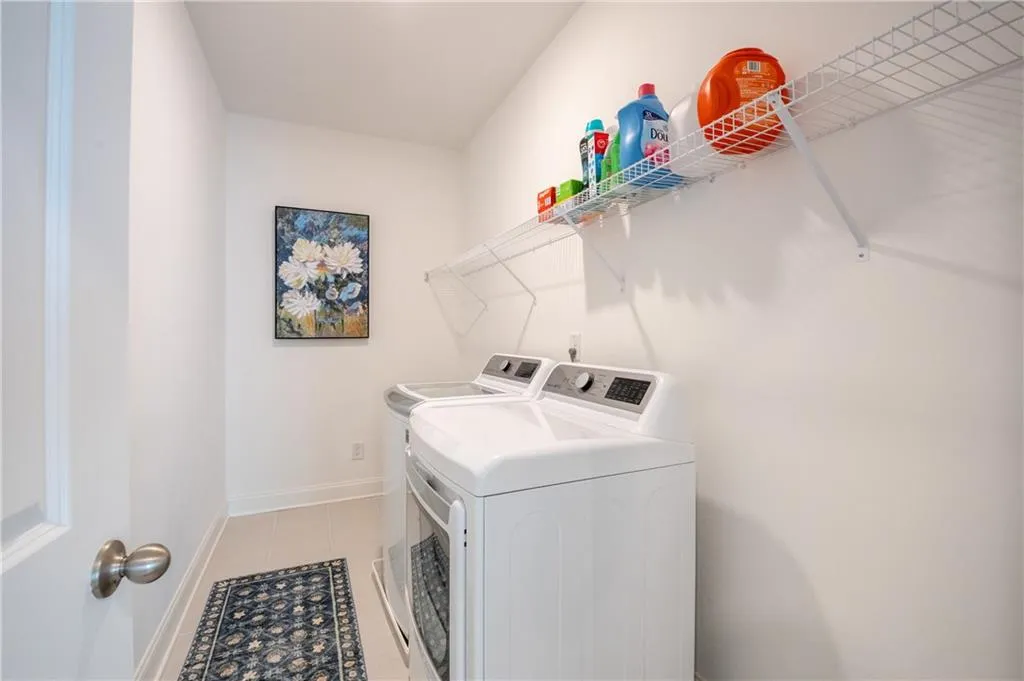 Laundry area with washer and clothes dryer and light tile patterned flooring