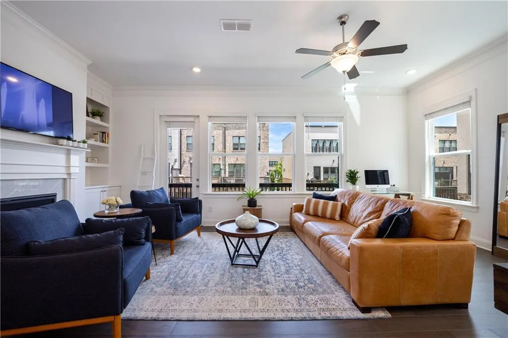 Living area featuring ornamental molding, plenty of natural light, a premium fireplace, wood finished floors, and recessed lighting