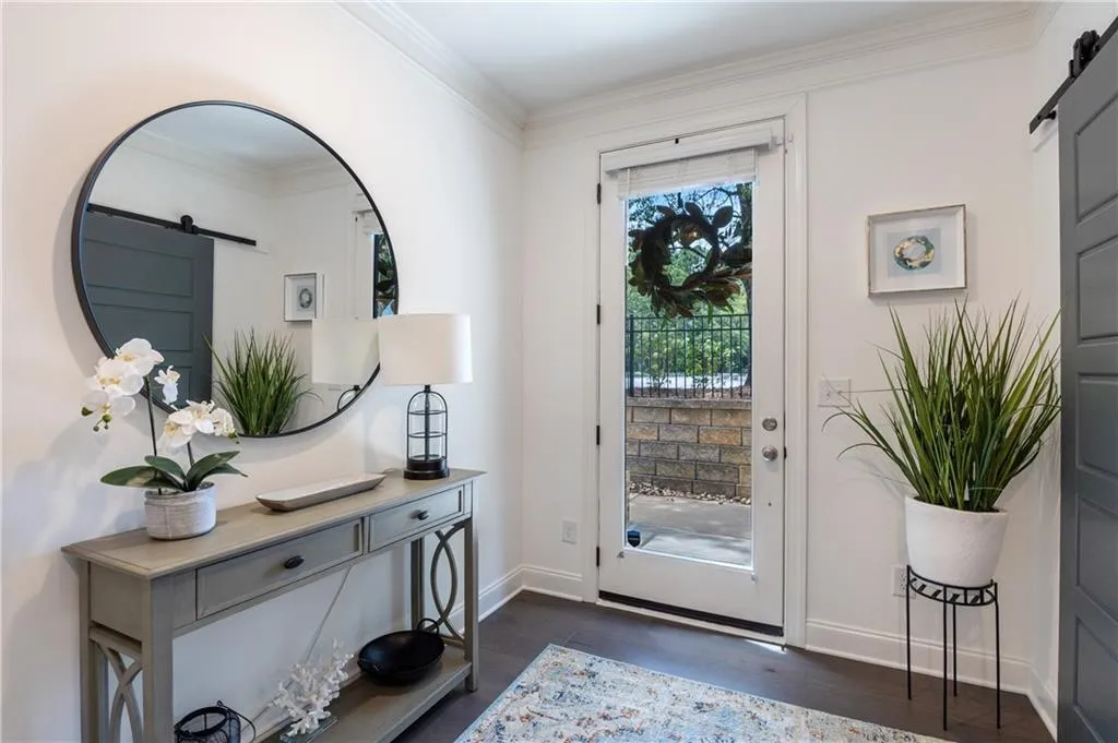 Doorway to outside with a barn door, crown molding, and wood finished floors