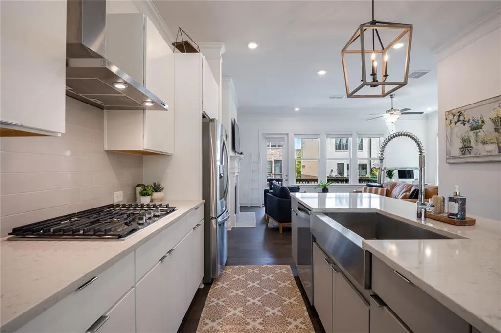 Kitchen featuring wall chimney exhaust hood, ornamental molding, open floor plan, light stone counters, and tasteful backsplash
