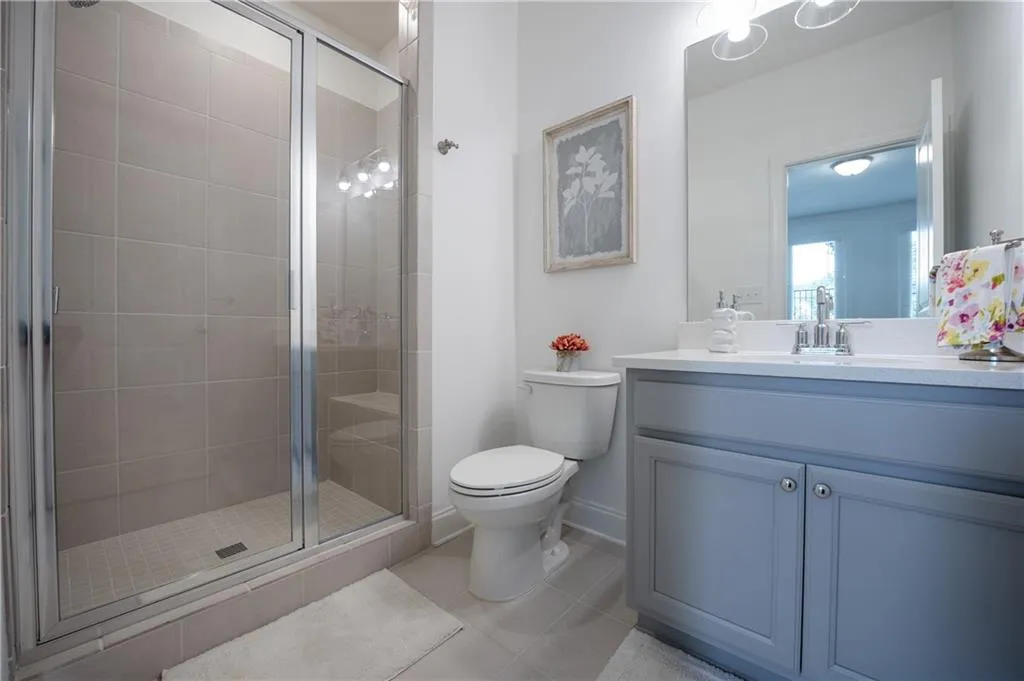 Full bath with a shower stall, vanity, and light tile patterned floors