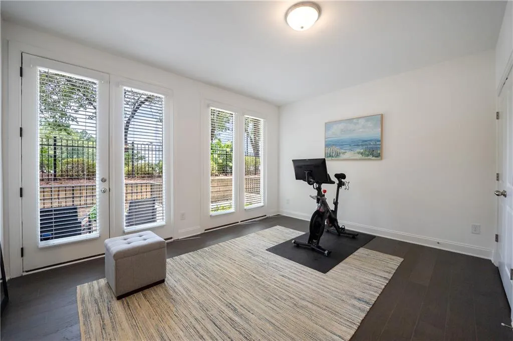 Workout room featuring dark wood-style floors and baseboards