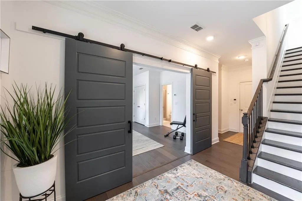 Entryway with a barn door, crown molding, stairway, dark wood-style floors, and recessed lighting