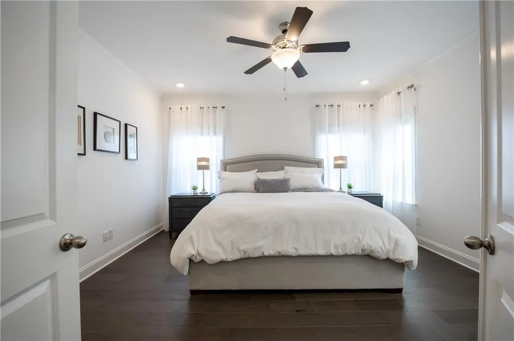 Bedroom featuring multiple windows, dark wood finished floors, ceiling fan, and crown molding