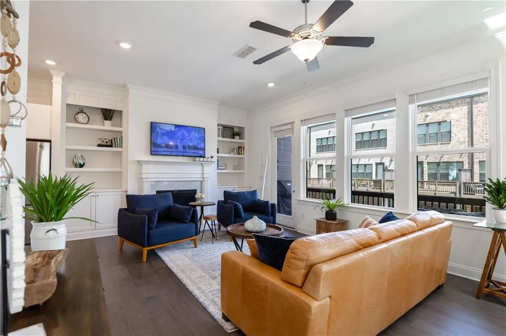 Living room with a high end fireplace, crown molding, dark wood finished floors, built in features, and recessed lighting