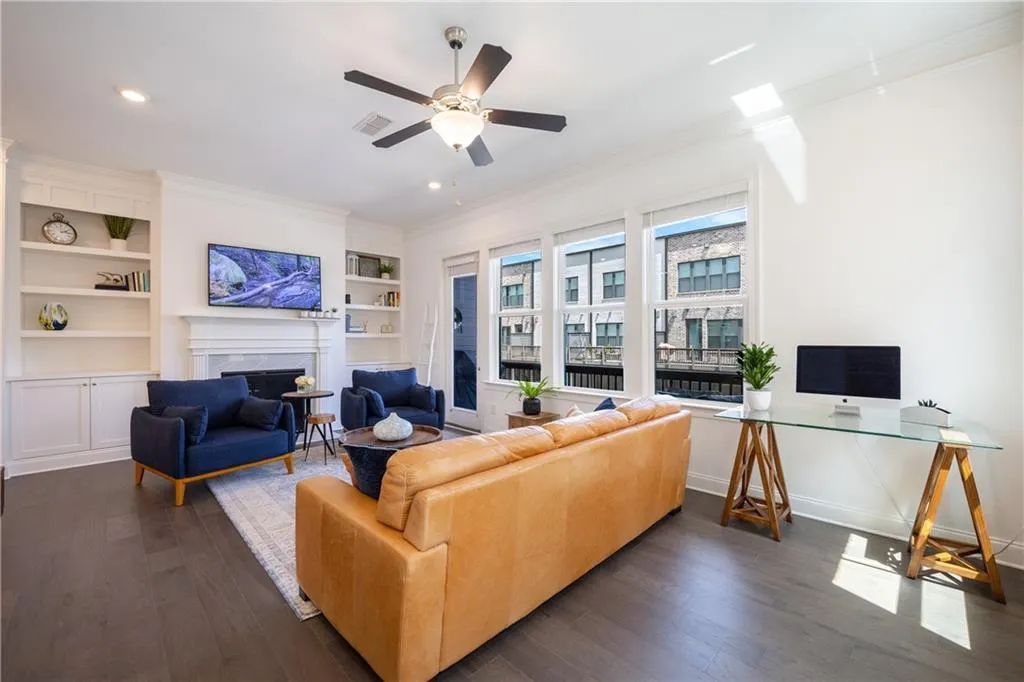 Living room featuring ornamental molding, a desk, dark wood-style floors, built in features, and a fireplace