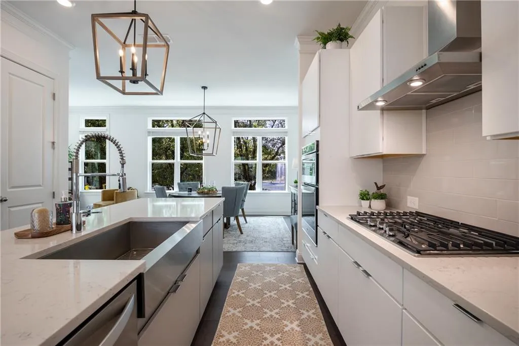 Kitchen with wall chimney exhaust hood, white cabinets, a chandelier, tasteful backsplash, and light stone counters