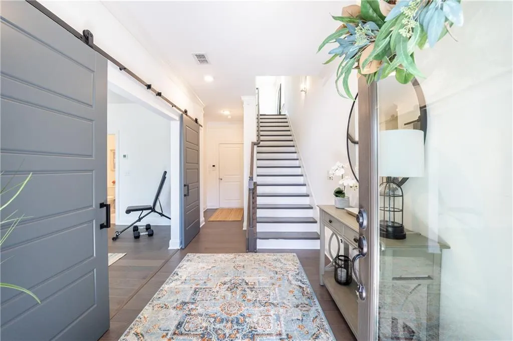 Entryway featuring a barn door, stairs, dark wood-style floors, recessed lighting, and ornamental molding