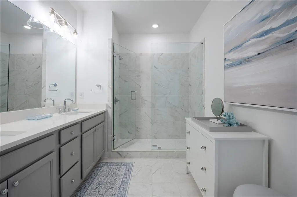 Full bathroom with double vanity, a marble finish shower, light marble finish floors, and recessed lighting