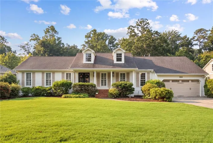 Classic Colonial-style residence featuring a symmetrical facade with dual dormers, white exterior trim, brick chimney detail, and a covered front entrance