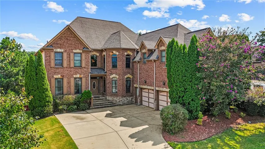 Brick exterior with stone accents, a multi-car garage, and mature landscaping