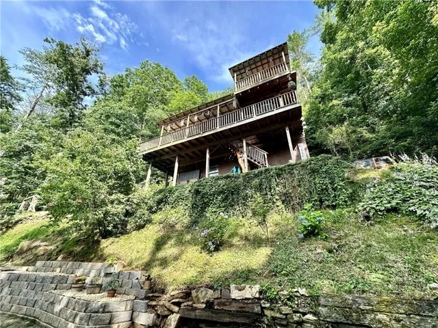 Multi-level home featuring wood balconies, natural wood siding, and an elevated position among mature trees