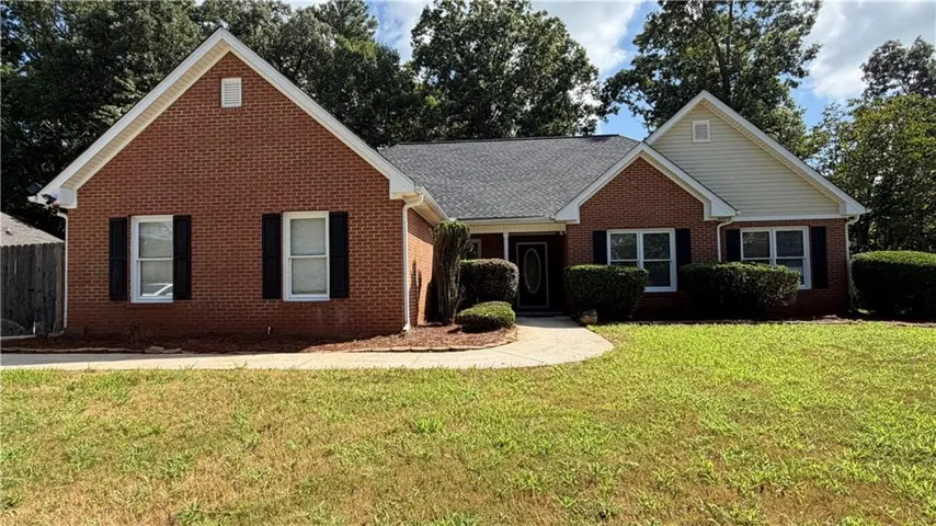 Charming brick residence featuring a gabled roofline, multiple windows with shutters, and a circular driveway approach