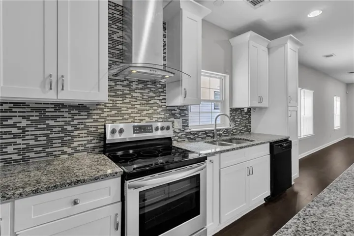 Kitchen featuring white shaker-style cabinetry, granite countertops, and a mosaic tile backsplash