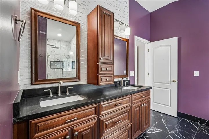 Dual vanity with dark wood cabinetry, black countertops, and undermount sinks